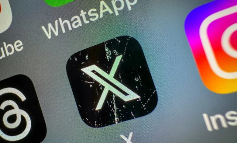 Close-up of the X app icon on a smartphone screen, next to WhatsApp and Instagram.