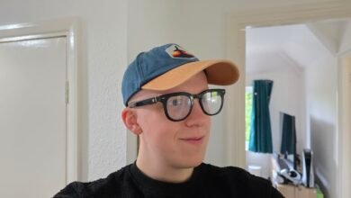 Young person wearing a blue baseball cap and black-rimmed glasses