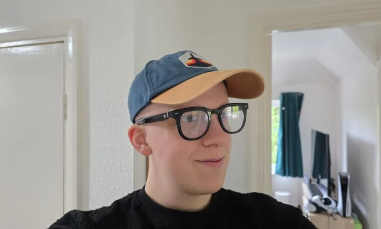 Young person wearing a blue baseball cap and black-rimmed glasses