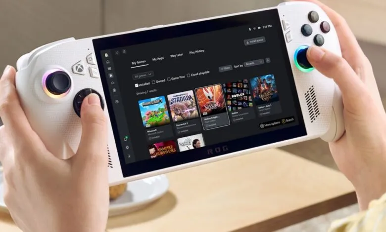 Hands holding a white handheld gaming device displaying a game library with Xbox Game Pass titles.