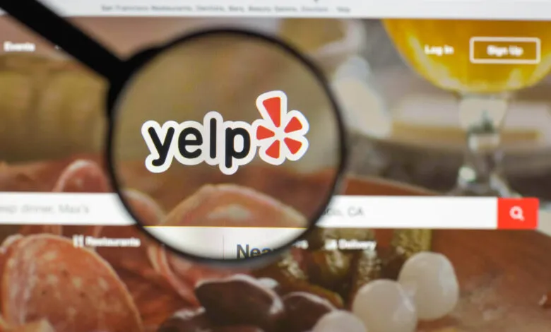 Magnifying glass over the Yelp logo on a computer screen displaying the website.