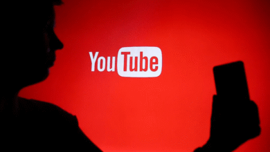 Silhouette of a person holding a smartphone in front of the YouTube logo.