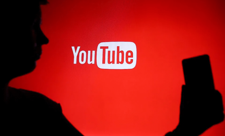 Silhouette of a person holding a smartphone in front of the YouTube logo.