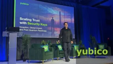 Man speaking on stage in front of a Yubico presentation about security keys.
