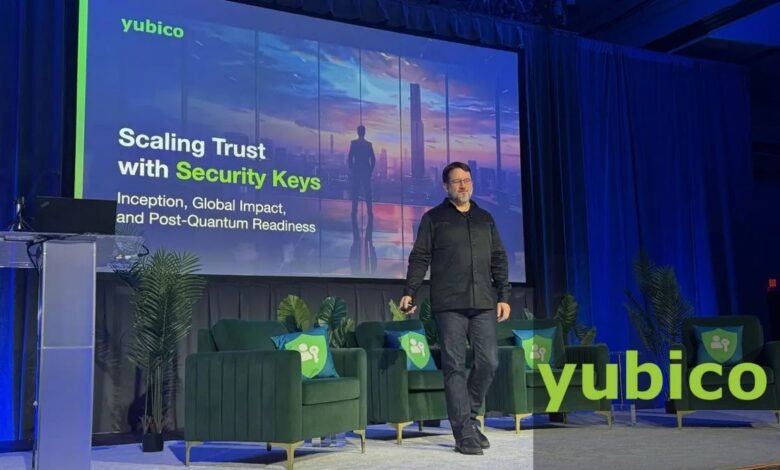 Man speaking on stage in front of a Yubico presentation about security keys.