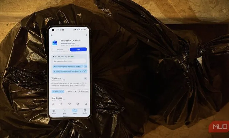 Smartphone displaying Microsoft Outlook app next to a black trash bag.