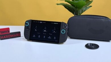 Handheld gaming PC displaying system performance metrics next to its carrying case.