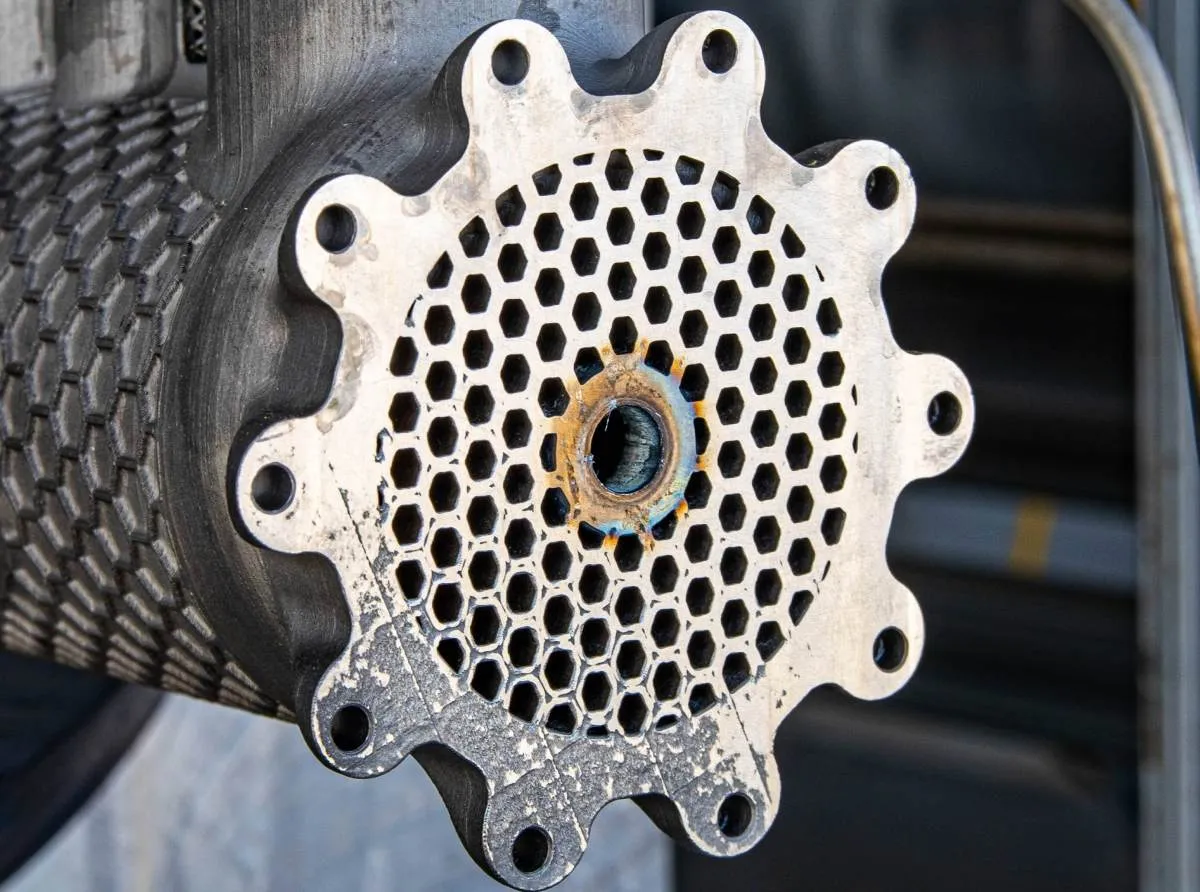 Close-up of a metal component with a hexagonal grid and a central opening.