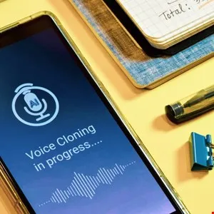 Smartphone screen displaying 'Voice Cloning in progress' with AI icon and waveform.