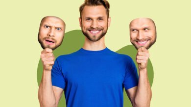 Man holding masks with different facial expressions, representing changing emotions.