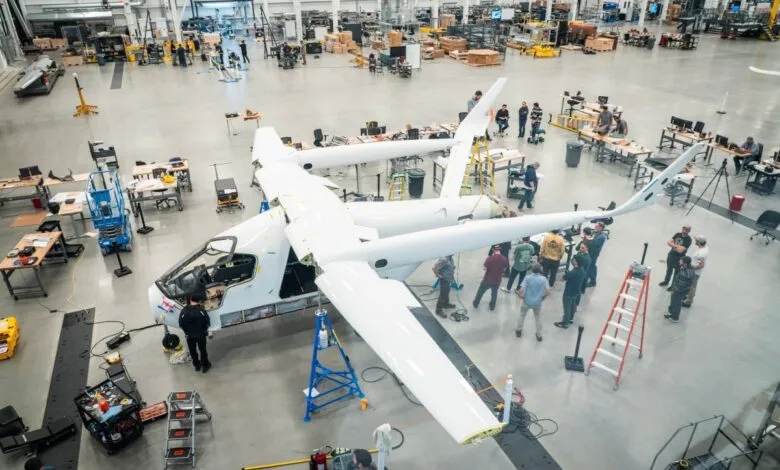 Team of engineers working on a white experimental aircraft in a large hangar.