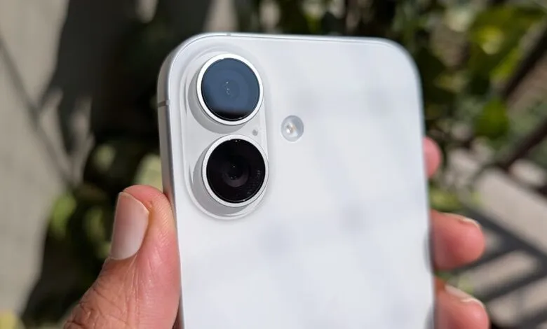 Close-up of a white smartphone's dual-lens camera system held by a thumb.