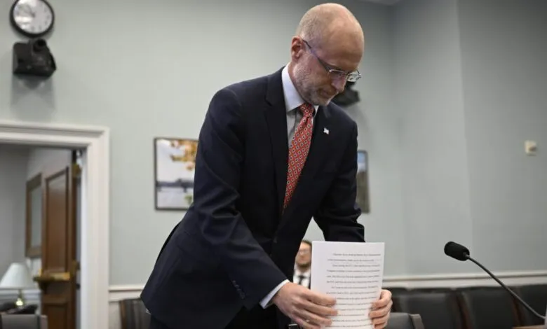 FCC Chairman Brendan Carr holds papers while testifying before a House committee.