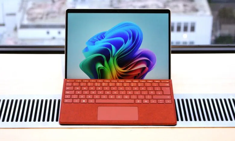 A red Microsoft Surface Pro with a vibrant Windows wallpaper displayed on screen.