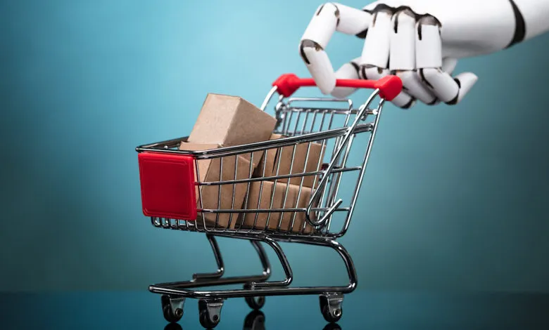 Robot hand pushing a shopping cart filled with cardboard boxes.