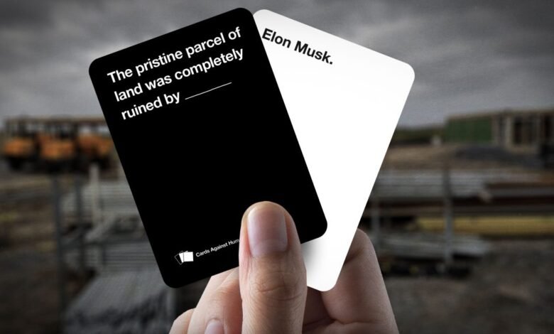 Hand holding Cards Against Humanity cards with 'Elon Musk' and a fill-in-the-blank prompt.