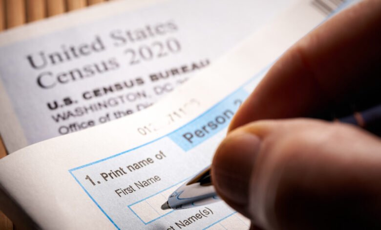 Close-up of a hand filling out a U.S. Census 2020 questionnaire with a pen.