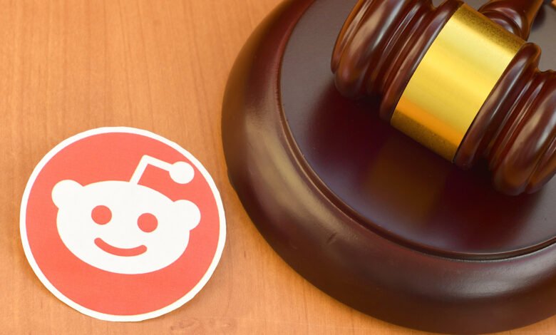Reddit logo next to a wooden judge's gavel on a wooden surface.
