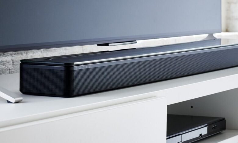 Sleek black soundbar with a glass top sits below a modern television.