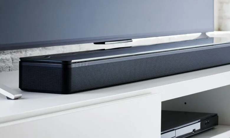 Sleek black soundbar with a glass top sits below a modern television.