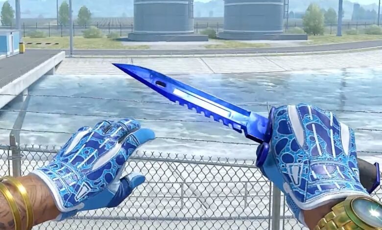 Player's hands wearing blue patterned gloves, holding a vibrant blue CS2 knife.