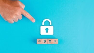 A finger points towards a large white padlock icon above four wooden blocks with security icons.