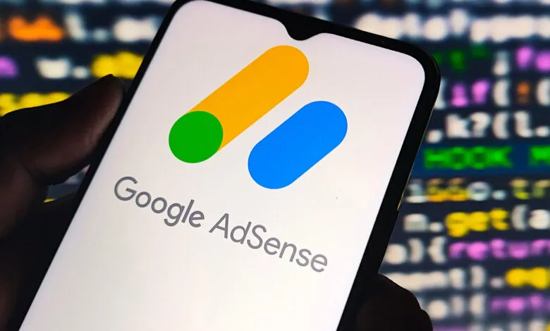 Google AdSense logo displayed on a smartphone screen with programming code in the background.