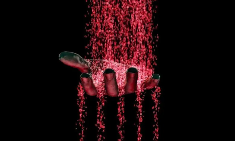 A hand holding a stream of red binary code falling like rain against a black background.