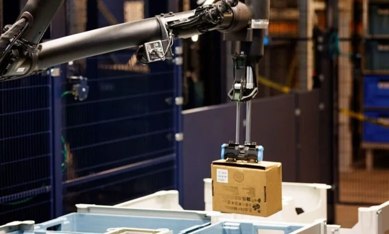 Robotic arm picking up a cardboard box in a warehouse setting.