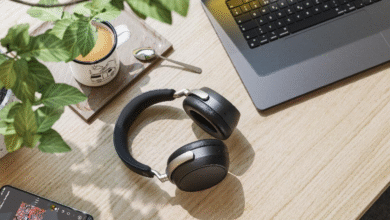 Overhead view of black headphones, a laptop, and a mug of coffee on a wooden desk.