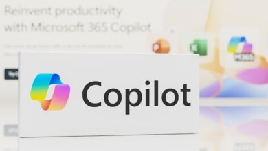 Microsoft Copilot logo and name on a white display, with blurred app icons in the background.