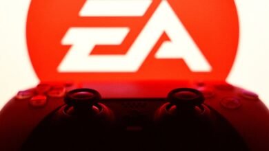 Close-up of a black game controller in silhouette against the glowing red EA logo.