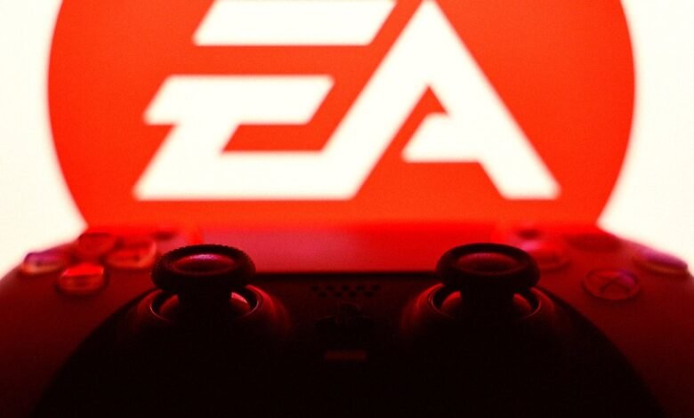 Close-up of a black game controller in silhouette against the glowing red EA logo.