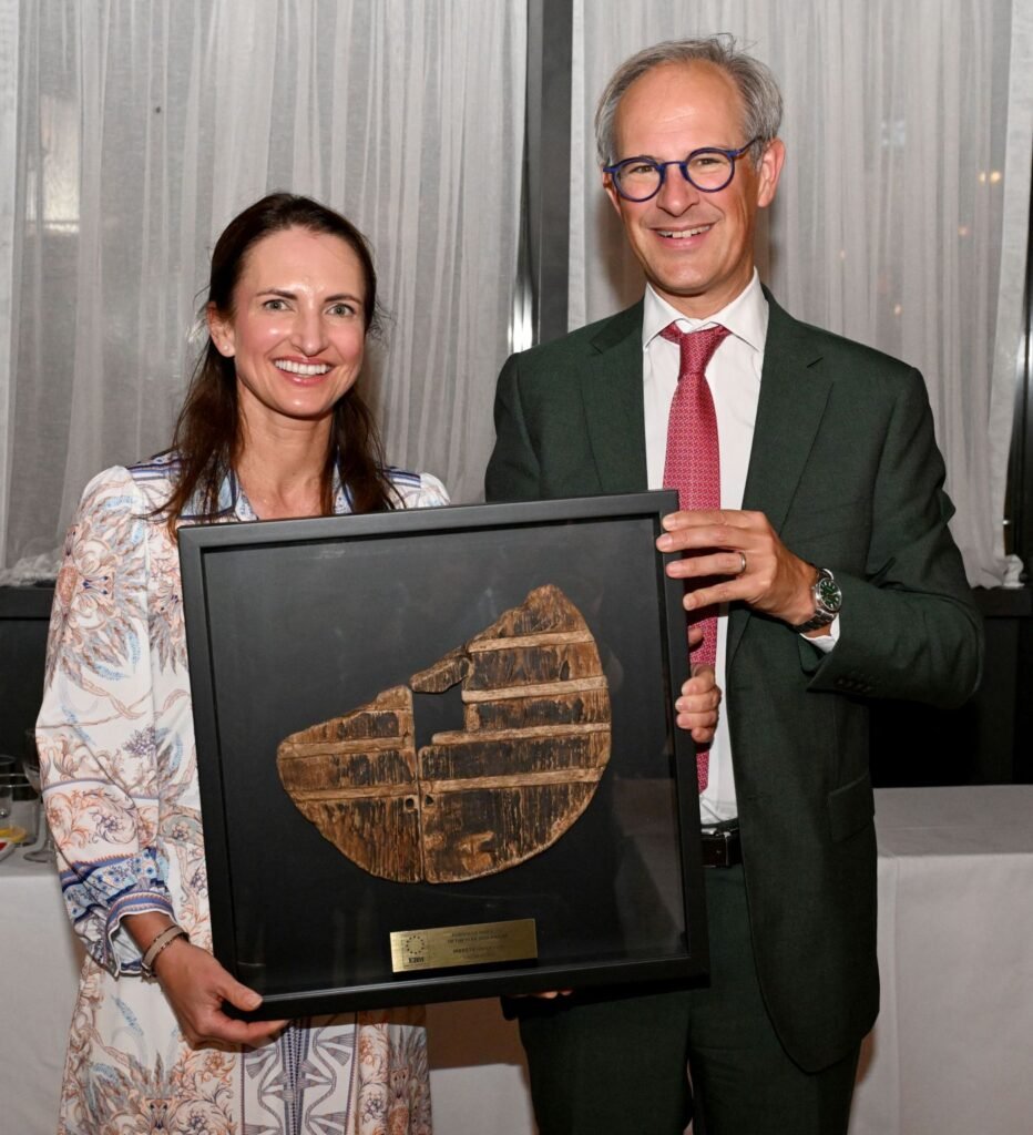 Man and woman holding a framed artifact with a plaque