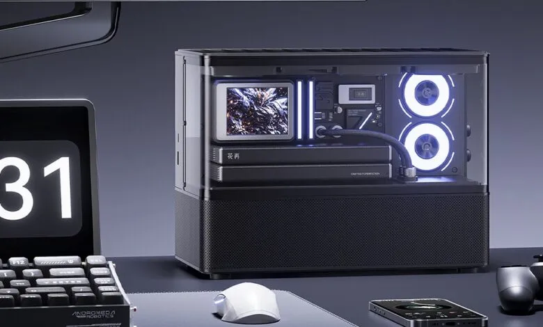 A modern, compact gaming PC with RGB lighting on a desk with a digital clock and controller.