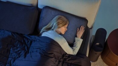 Woman sleeping peacefully on a bed with a smart mattress and dark blue comforter.