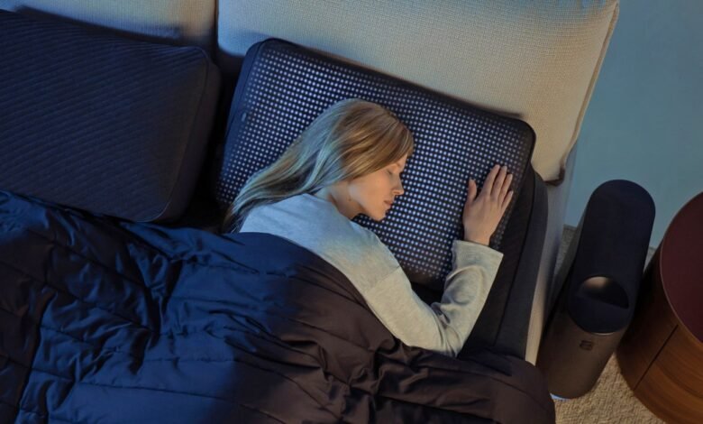 Woman sleeping peacefully on a bed with a smart mattress and dark blue comforter.