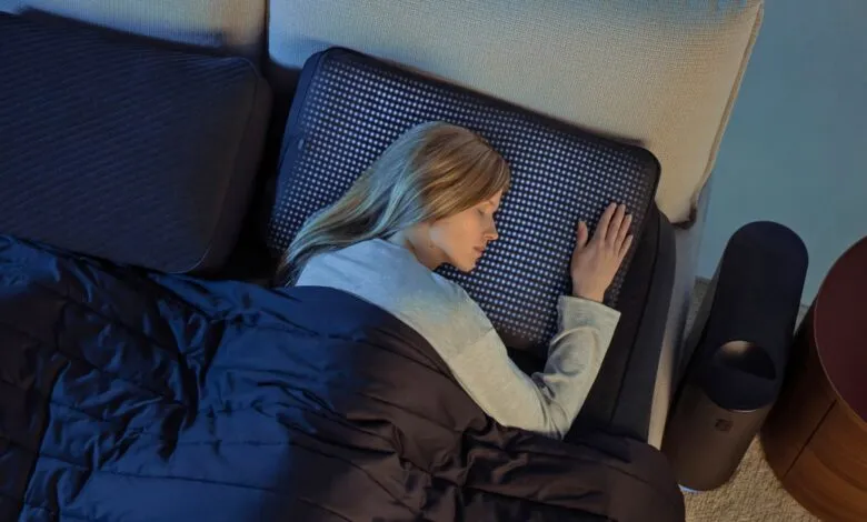 Woman sleeping peacefully on a bed with a smart mattress and dark blue comforter.