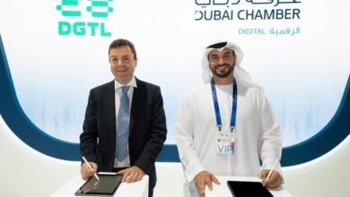 Two men signing digital documents on tablets at an event with Dubai Chamber branding.