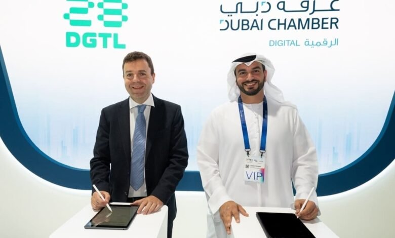 Two men signing digital documents on tablets at an event with Dubai Chamber branding.