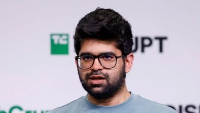 Close-up of a man with dark hair, beard, and glasses speaking.