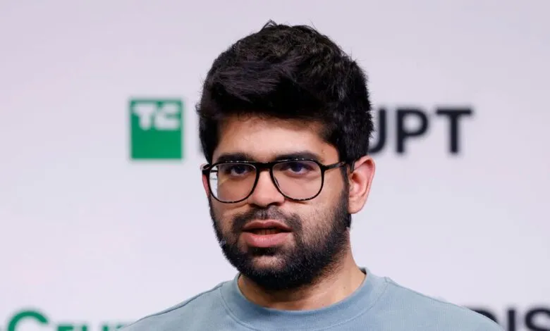 Close-up of a man with dark hair, beard, and glasses speaking.