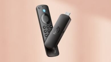 Black Amazon Fire TV Stick and remote control on a soft peach background.