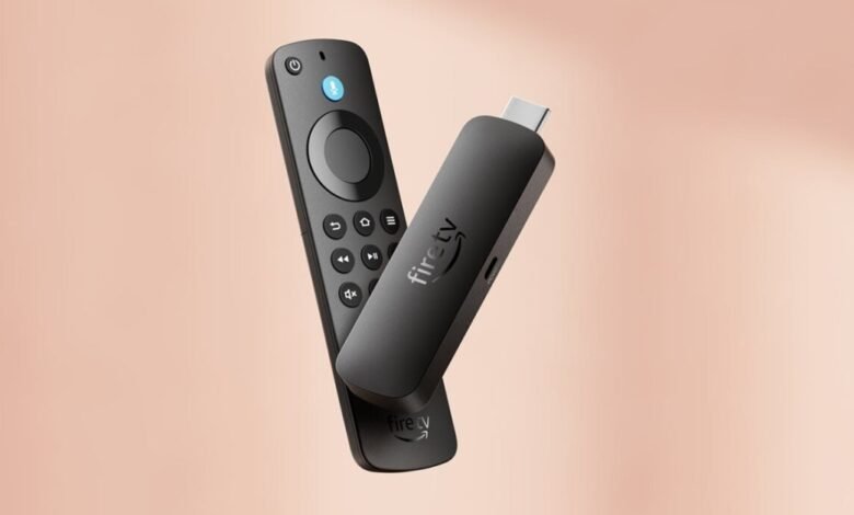 Black Amazon Fire TV Stick and remote control on a soft peach background.
