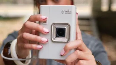 Close-up of a person holding a white Fujifilm Instax mini LiPlay+ camera