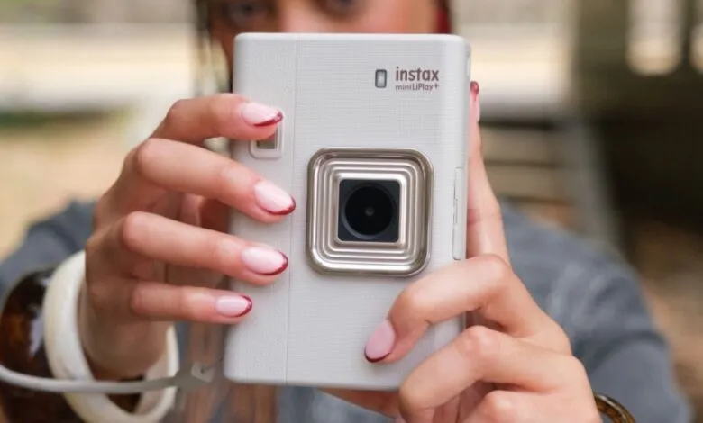 Close-up of a person holding a white Fujifilm Instax mini LiPlay+ camera