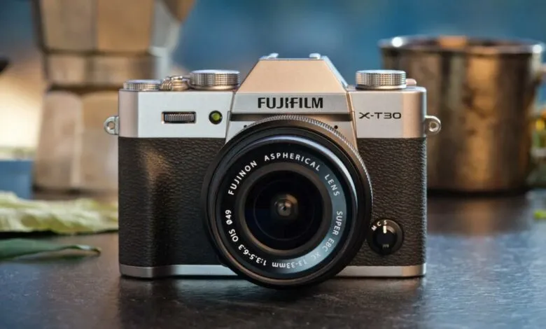 Close-up of a silver Fujifilm X-T30 camera with a black lens.