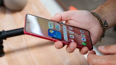 Close-up of a person holding a red Samsung Galaxy Z Flip smartphone, showing the home screen.