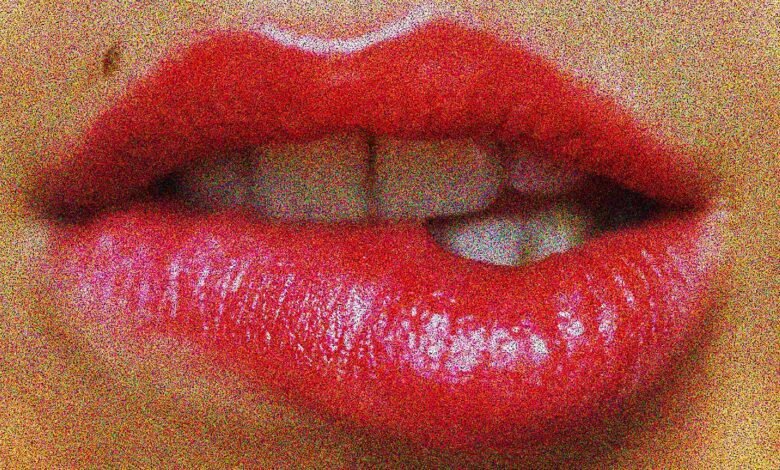Close-up of red lips biting down, with teeth visible.