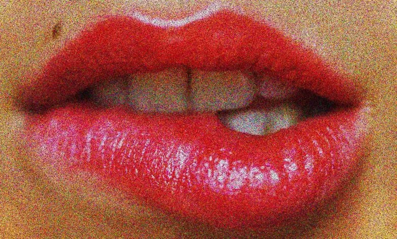 Close-up of red lips biting down, with teeth visible.